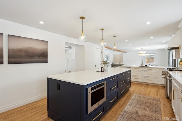 kitchen with light wood-type flooring, pendant lighting, white cabinets, and a center island