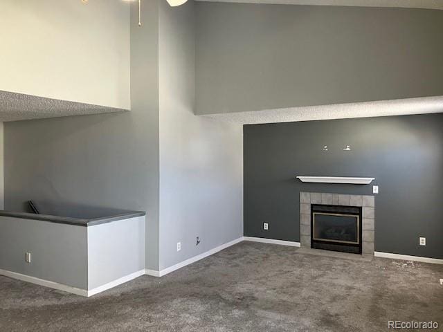 unfurnished living room featuring carpet floors, a fireplace, a high ceiling, ceiling fan, and baseboards