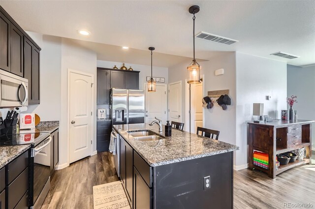 4355 24th Street Rd Unit 2804, Greeley, CO 80634 - kitchen featuring stainless steel appliances, a sink, dark wood-style flooring, light stone counters, and a kitchen island with sink