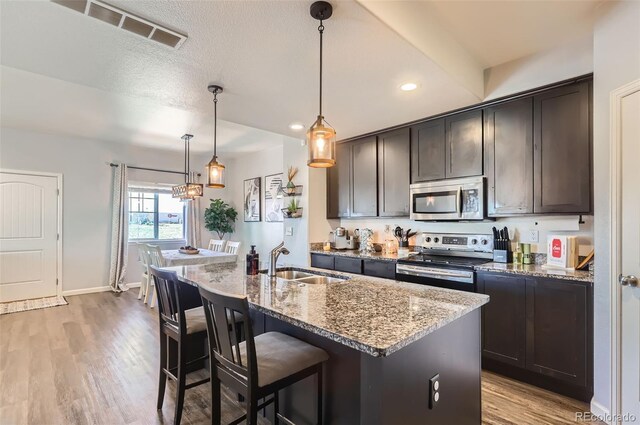 4355 24th Street Rd Unit 2804, Greeley, CO 80634 - kitchen featuring stainless steel appliances, a sink, stone counters, light wood-type flooring, and a kitchen bar