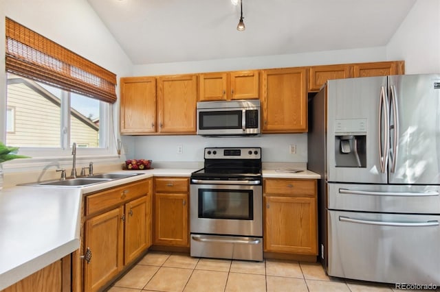 kitchen featuring appliances with stainless steel finishes, lofted ceiling, light tile patterned floors, and sink