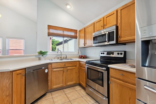 kitchen with lofted ceiling, light tile patterned floors, stainless steel appliances, and sink