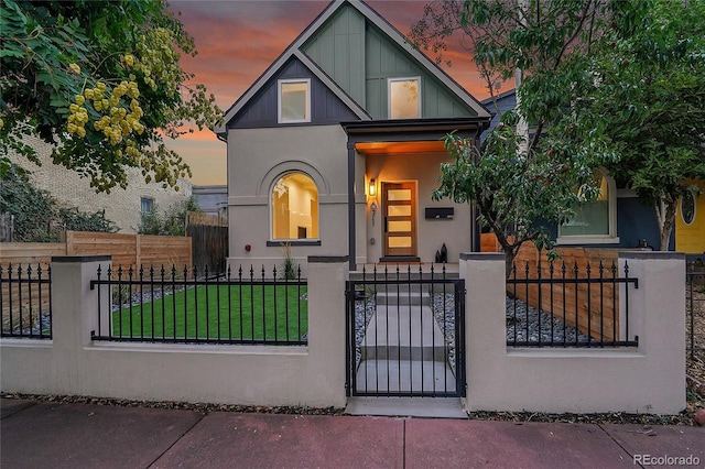 view of front of house with a fenced front yard, a gate, board and batten siding, and stucco siding