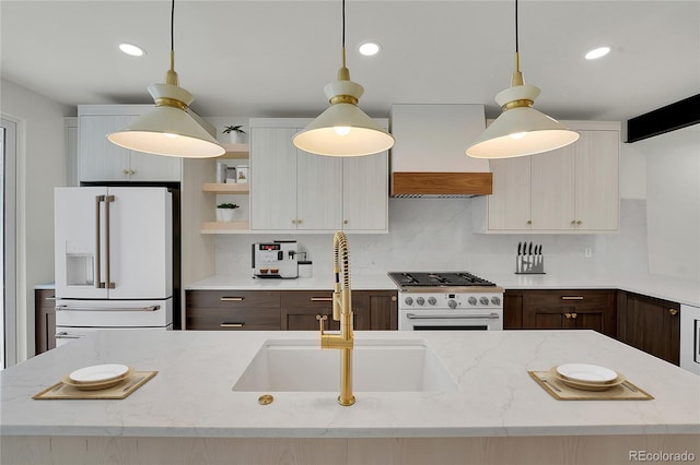 kitchen with premium range hood, white refrigerator with ice dispenser, a sink, gas stove, and pendant lighting