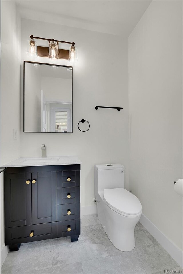 bathroom with marble finish floor, baseboards, vanity, and toilet