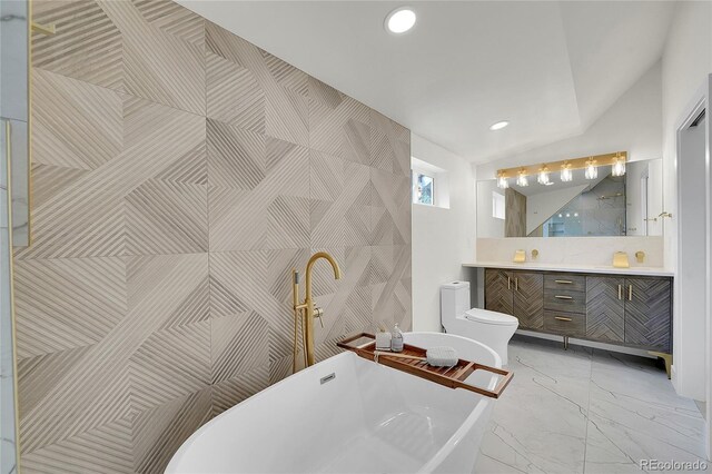 bathroom with a tub, toilet, vanity, and vaulted ceiling