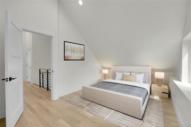 bedroom featuring lofted ceiling, light wood-style flooring, and baseboards