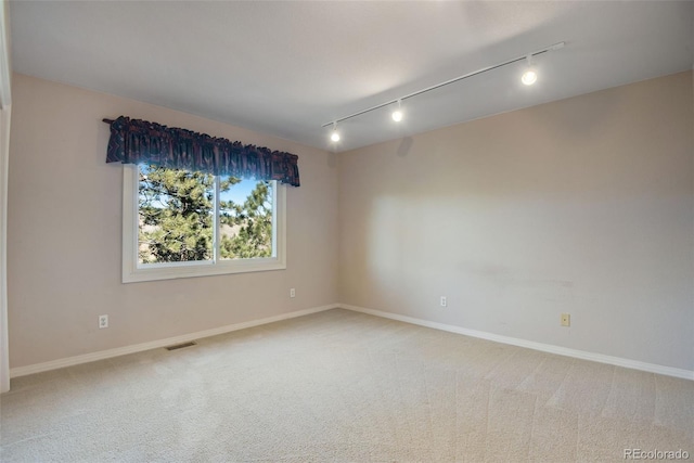 carpeted spare room with rail lighting