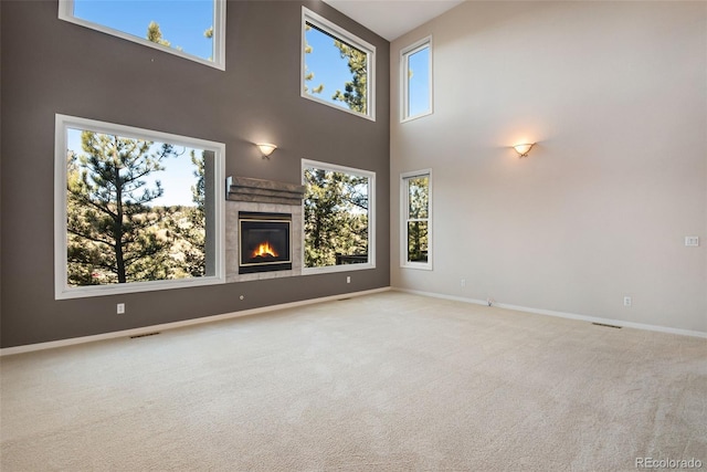 unfurnished living room with a fireplace, a high ceiling, and light carpet