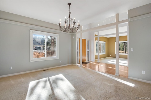 unfurnished dining area with light colored carpet and a chandelier