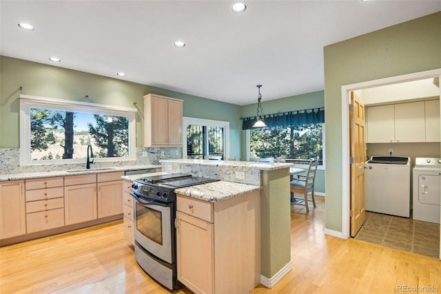 kitchen featuring washing machine and dryer, sink, stainless steel stove, and light brown cabinets