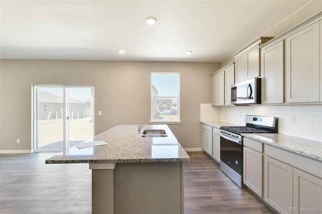 9910 Biscay St, Commerce City, CO 80022 - kitchen with stainless steel appliances, wood finished floors, an island with sink, decorative backsplash, and recessed lighting