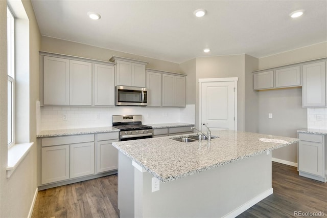 9910 Biscay St, Commerce City, CO 80022 - kitchen with appliances with stainless steel finishes, dark wood-style floors, tasteful backsplash, an island with sink, and recessed lighting
