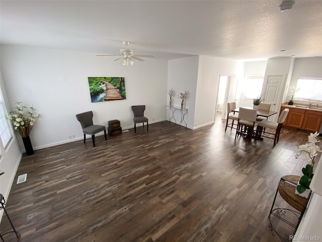 sitting room with ceiling fan, dark wood-type flooring, sink, and a textured ceiling