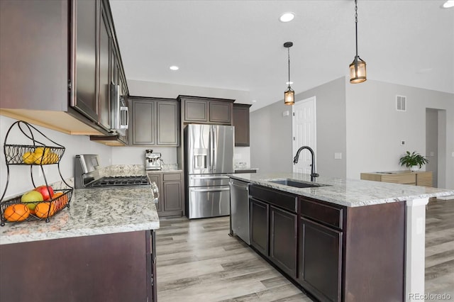 kitchen featuring sink, light hardwood / wood-style flooring, an island with sink, decorative light fixtures, and stainless steel appliances