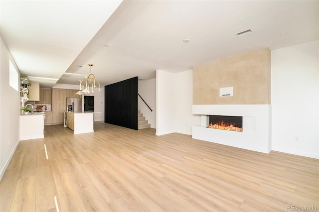 unfurnished living room featuring light wood-type flooring, a fireplace, stairway, and baseboards