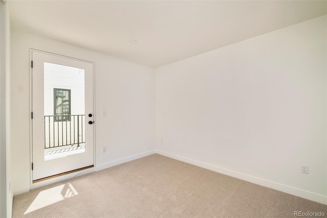 unfurnished room with light colored carpet and baseboards