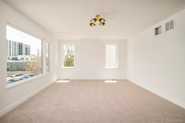 unfurnished room featuring light carpet and baseboards