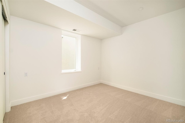 spare room featuring light colored carpet and baseboards