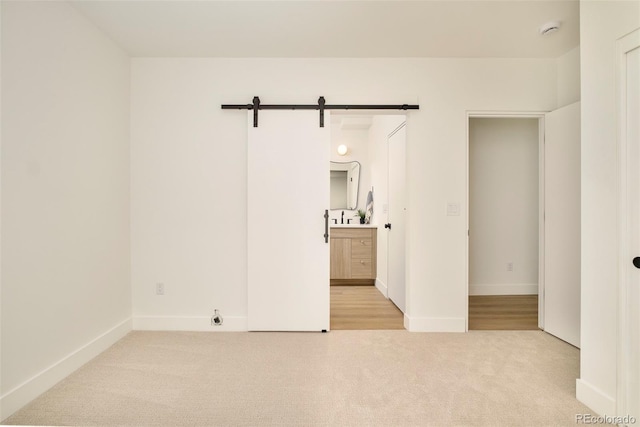 spare room with carpet floors, a smoke detector, a barn door, and baseboards