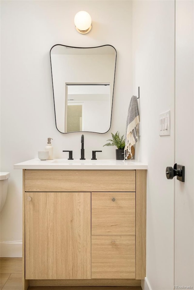 half bath with vanity, baseboards, and toilet