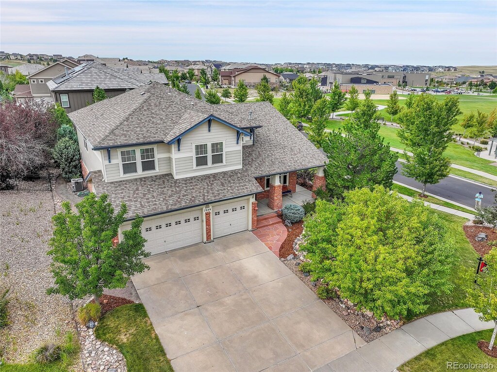 7949 S Blackstone Pkwy, Aurora, CO 80016 - view of front of house with an attached garage, driveway, brick siding, a shingled roof, and covered porch