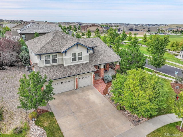 7949 S Blackstone Pkwy, Aurora, CO 80016 - view of front of house with an attached garage, driveway, brick siding, a shingled roof, and covered porch