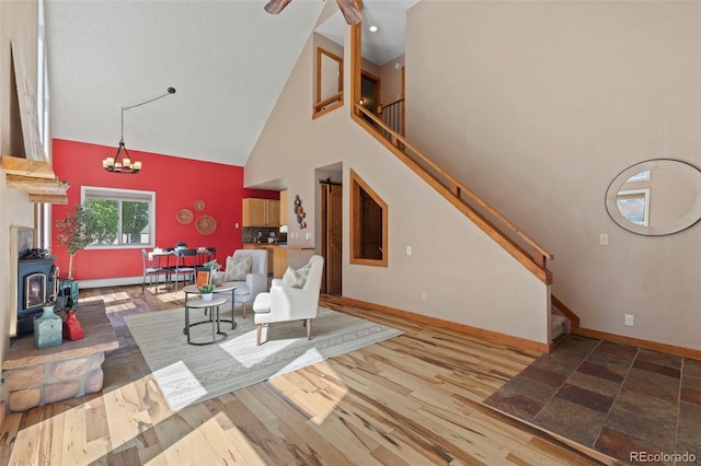 1345 Leslie Cir, Woodland Park, CO 80863 - living area featuring high vaulted ceiling, a wood stove, stairs, a chandelier, and wood finished floors