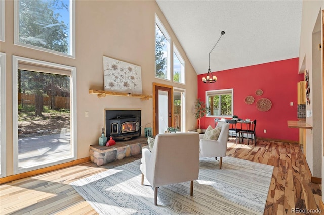 1345 Leslie Cir, Woodland Park, CO 80863 - living room featuring high vaulted ceiling, a wood stove, wood finished floors, and a chandelier
