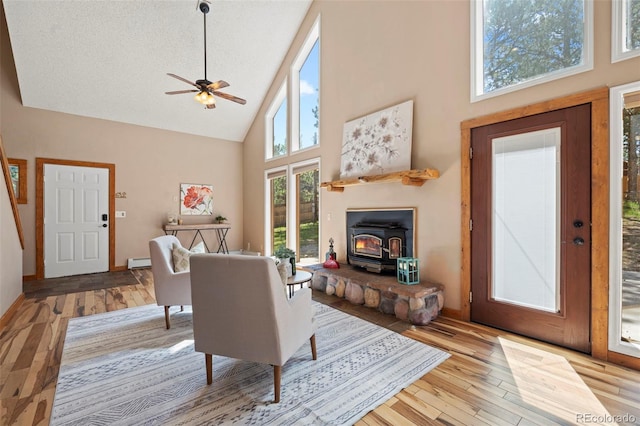 1345 Leslie Cir, Woodland Park, CO 80863 - living room with high vaulted ceiling, a wood stove, wood finished floors, a ceiling fan, and baseboard heating