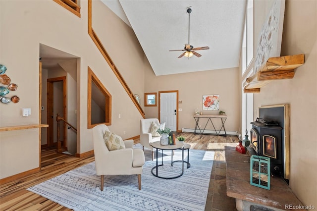 1345 Leslie Cir, Woodland Park, CO 80863 - living room with high vaulted ceiling, wood finished floors, a baseboard heating unit, a ceiling fan, and a wood stove