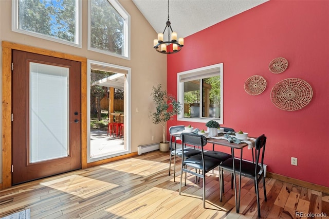 1345 Leslie Cir, Woodland Park, CO 80863 - dining room with a chandelier, light wood finished floors, a baseboard radiator, and high vaulted ceiling