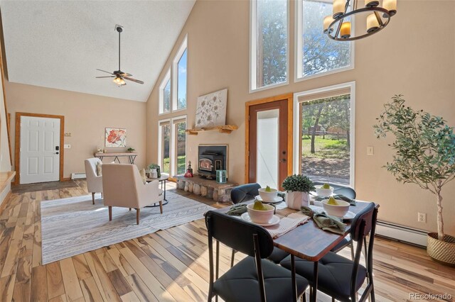 1345 Leslie Cir, Woodland Park, CO 80863 - dining area featuring high vaulted ceiling, light wood-style floors, a ceiling fan, a chandelier, and a baseboard heating unit