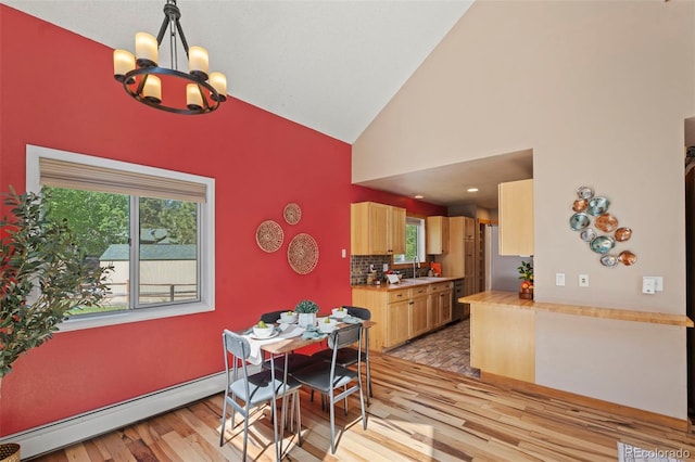 1345 Leslie Cir, Woodland Park, CO 80863 - dining room featuring baseboard heating, light wood-type flooring, a chandelier, plenty of natural light, and high vaulted ceiling