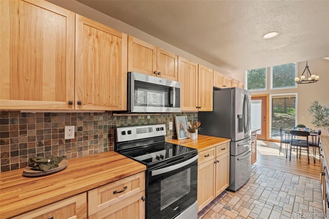 1345 Leslie Cir, Woodland Park, CO 80863 - kitchen with appliances with stainless steel finishes, butcher block counters, light brown cabinetry, tasteful backsplash, and a textured ceiling