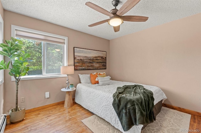 1345 Leslie Cir, Woodland Park, CO 80863 - bedroom with baseboard heating, a textured ceiling, wood finished floors, and ceiling fan