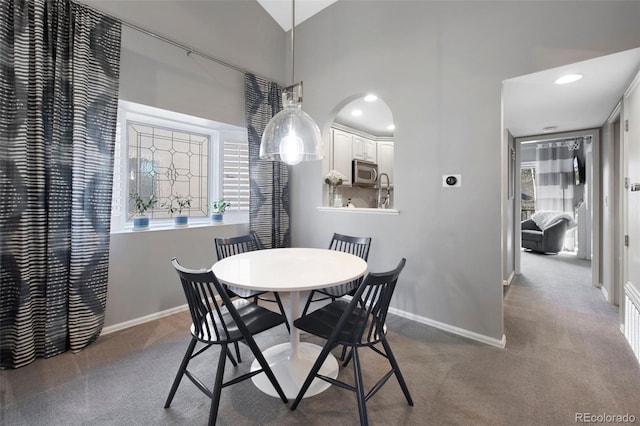 dining space with carpet floors and high vaulted ceiling