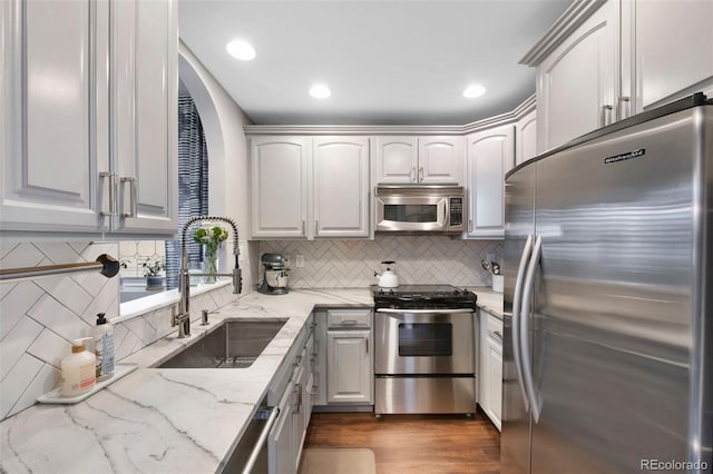 kitchen featuring backsplash, sink, dark hardwood / wood-style floors, light stone countertops, and stainless steel appliances