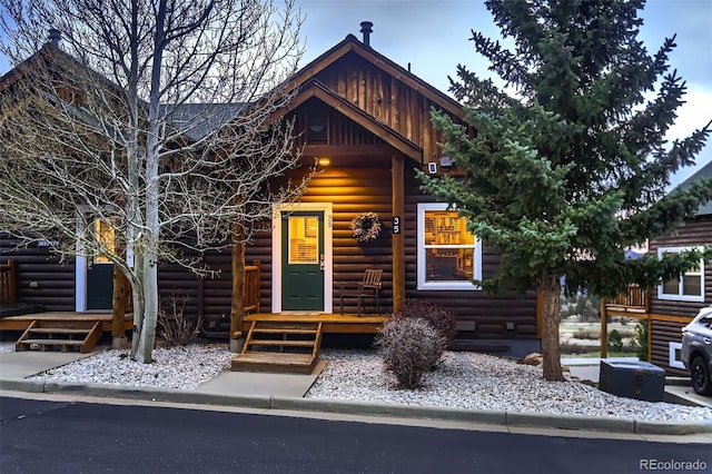 view of front of property featuring covered porch and faux log siding