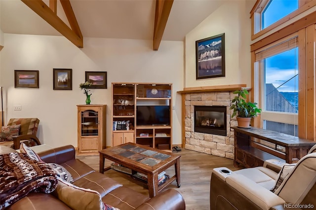 living room with a fireplace, vaulted ceiling with beams, a healthy amount of sunlight, and wood finished floors