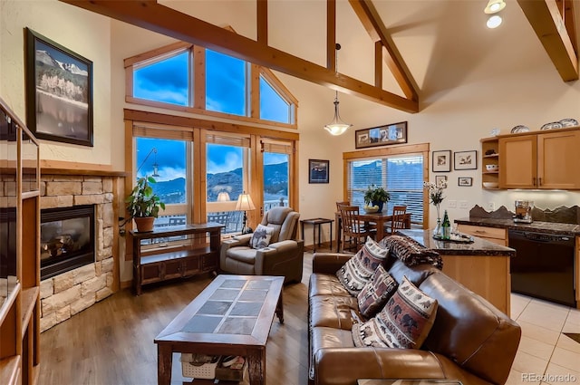 living area featuring light wood finished floors, a fireplace, beamed ceiling, and high vaulted ceiling