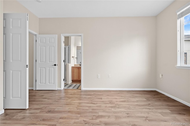 unfurnished bedroom with light hardwood / wood-style flooring and ensuite bathroom