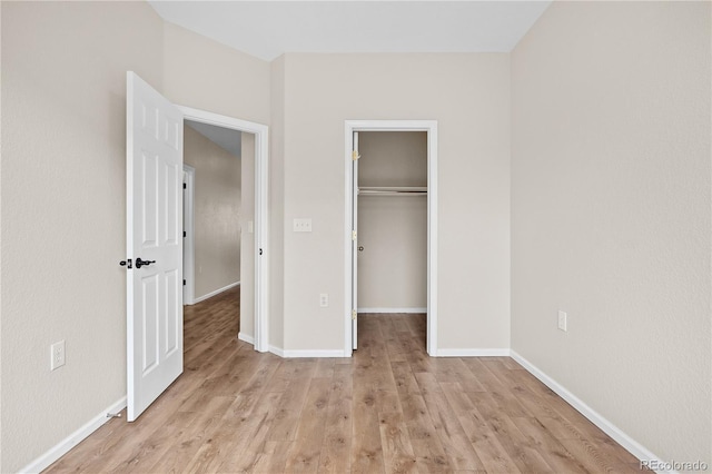 unfurnished bedroom with a spacious closet, light hardwood / wood-style flooring, and a closet