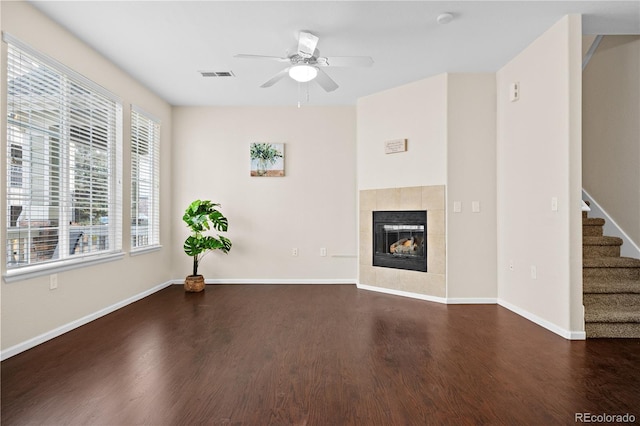 unfurnished living room with ceiling fan, dark hardwood / wood-style flooring, and a tile fireplace