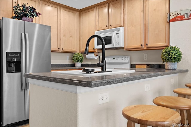 kitchen featuring light brown cabinetry, sink, stainless steel fridge, kitchen peninsula, and a kitchen breakfast bar