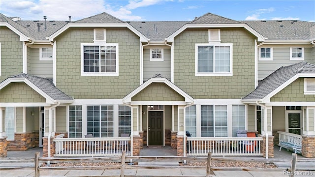 multi unit property with a porch, roof with shingles, and stone siding