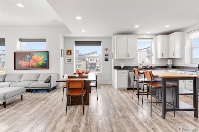 kitchen with dishwasher, light wood-style floors, a wealth of natural light, and decorative backsplash