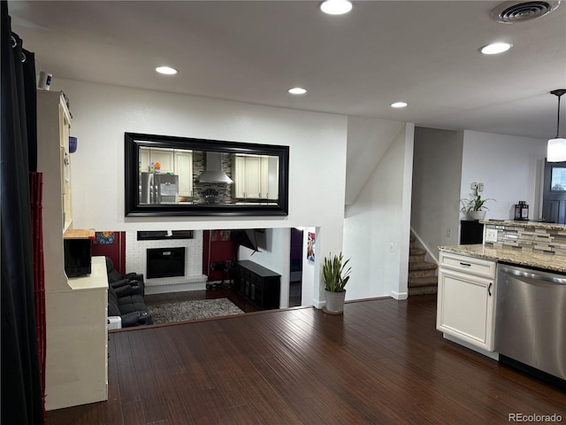 7132 Xavier Way, Westminster, CO 80030 - kitchen with appliances with stainless steel finishes, wall chimney exhaust hood, a fireplace, baseboards, and white cabinetry