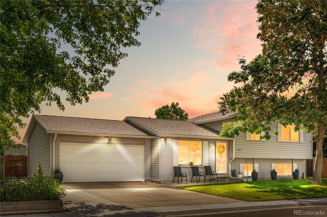7132 Xavier Way, Westminster, CO 80030 - split level home featuring an attached garage, concrete driveway, and brick siding