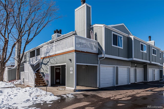 view of front of house with an attached garage, a chimney, and stairway